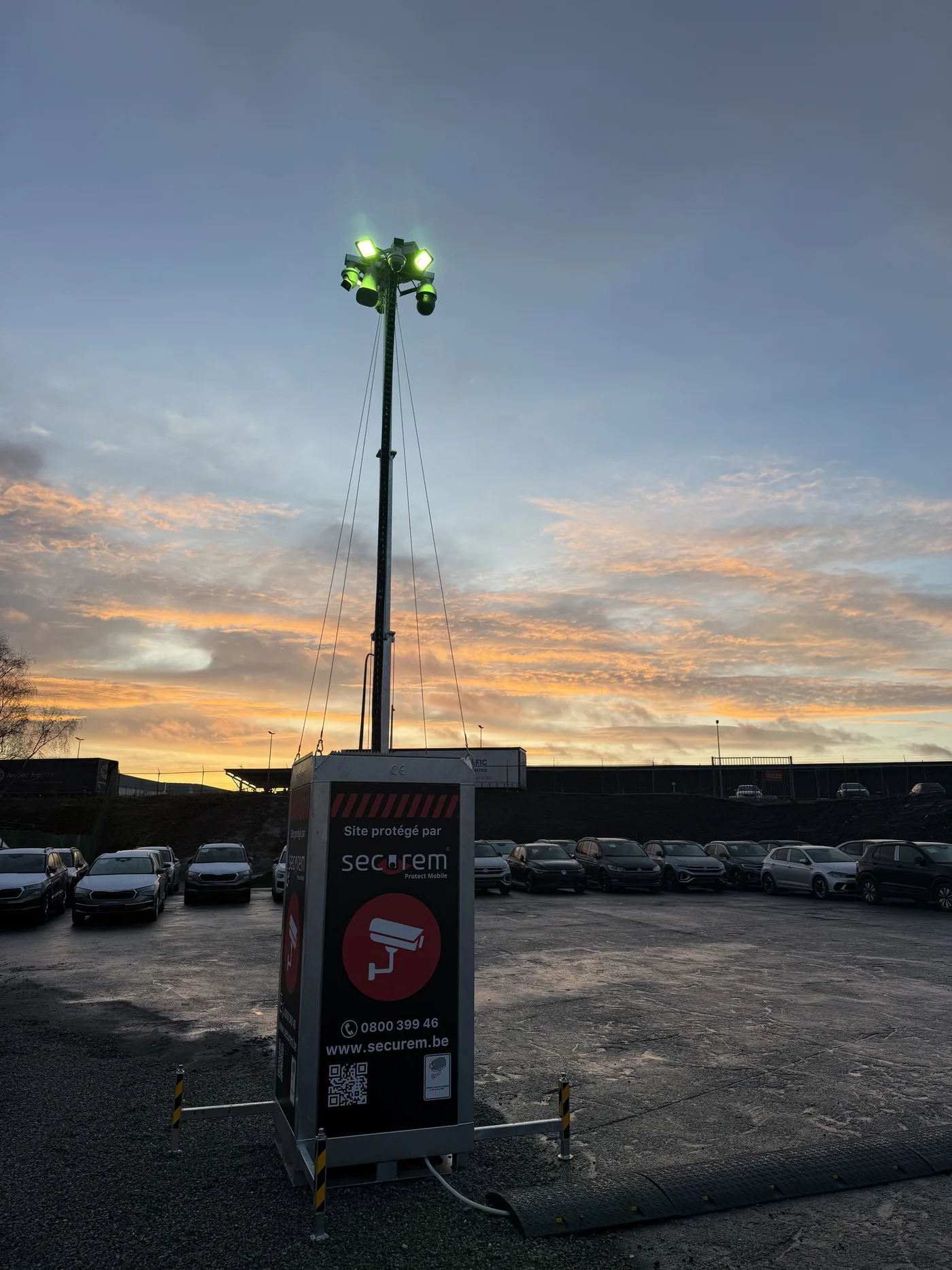 Mât Securem Protect Mobile éclairé au coucher du soleil, surveillant un parking