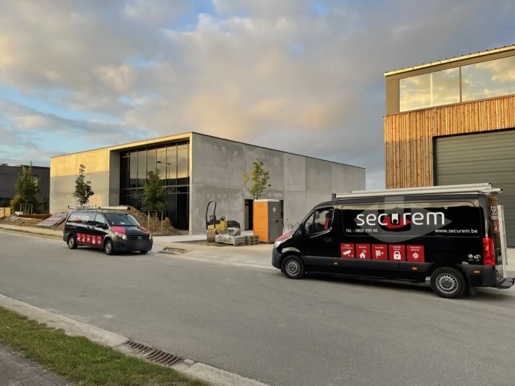 Deux camionnettes Securem garées devant un bâtiment professionnel récent